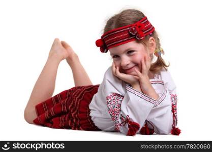 Little girl in the national Ukrainian costume lying on his stomach on the white background