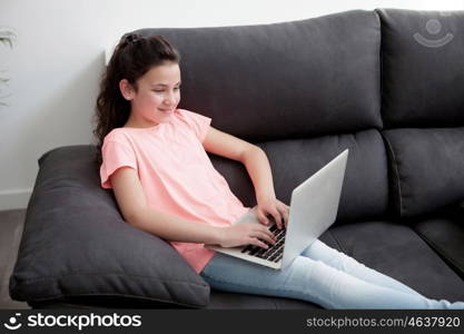 Little girl in the sofa at home with a laptop