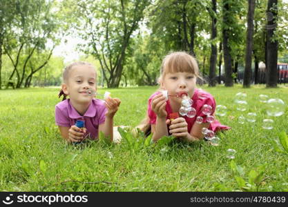 Little girl in the summer park blowing bubbles