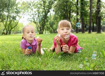 Little girl in the summer park blowing bubbles