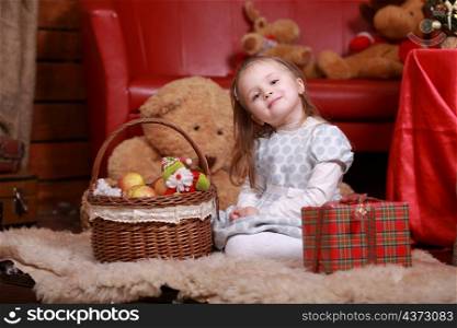 little girl in white polka dots dress having fun in the Christmas studio. Christmas tree, teddy bear and basket with gifts on the front of.. little girl in white polka dots dress having fun in the Christmas studio. Christmas tree, teddy bear and basket with gifts on the front of
