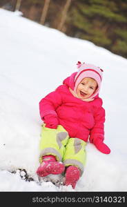 little girl in winter parka sits on snow