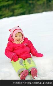 little girl in winter parka sits on snow