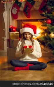 Little girl in wool sweater holding red Christmas gift box