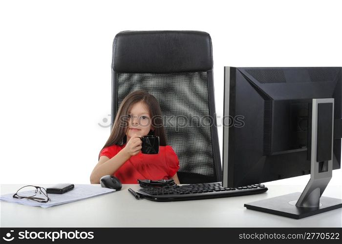 Little girl is drinking coffee in front of a computer. Isolated on white background