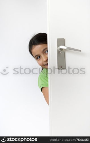 Little girl is hiding behind the door