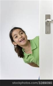 Little girl is hiding behind the door for fun