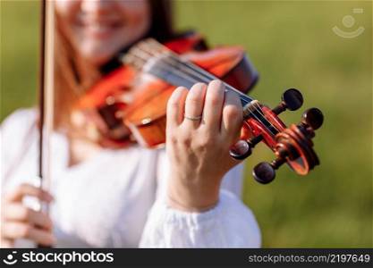 little girl is playing violin outdoor with garden in the background on sunny summer day. Image with selective focus and copy space. little girl is playing violin outdoor with garden in the background on sunny summer day. Image with selective focus and copy space.