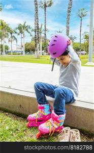 Little girl is putting on her protective helmet to skate in the park