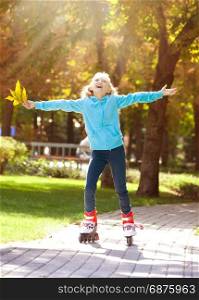 Little Girl is Riding on Rollers and Enjoying a Sunny Autumn Day in Park