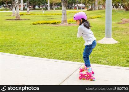 Little girl is skating with her roller skates on the rink