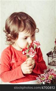 Little girl is smelling the roses. Close up face. Girl with flowers