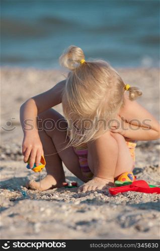 little girl joys with her toys on a beach.
