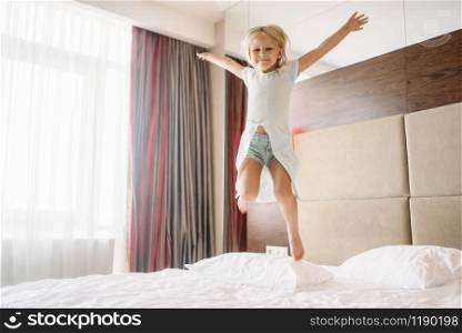 Little girl jumping on the bed in bedroom at home. A truly carefree childhood, happy time