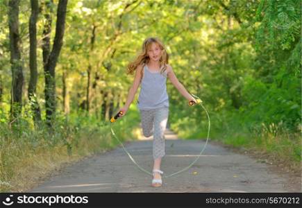 little girl jumps over rope in forest