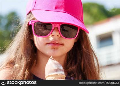 Little girl kid eating ice cream on beach. Summer.. Kid eating gelato soft serve ice cream on beach. Little girl in sunglasses enjoying summer holidays vacation outdoor.