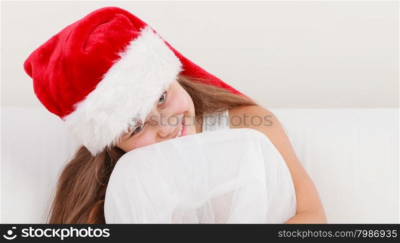 Little girl kid in santa claus hat. Christmas.. Cute little girl kid in red santa claus hat and white dress sitting on sofa couch. Chrtistmas holiday season.