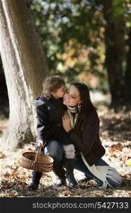 Little girl kissing her mum in woods