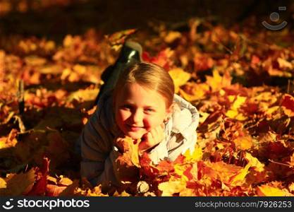 little girl laying in yellow leaves in the autumn park