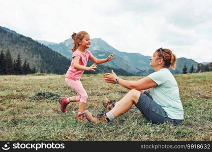 Little girl laying playing on grass enjoying summer day. Happy child playing in the field during vacation trip in mountains. Little girl laying playing on grass enjoying summer day during vacation trip