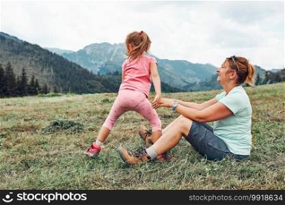 Little girl laying playing on grass enjoying summer day. Happy child playing in the field during vacation trip in mountains. Little girl laying playing on grass enjoying summer day during vacation trip