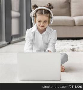 little girl listening her teacher through headphones home