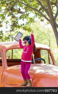 Little girl listening to music on the tablet with her headphones in the truck car