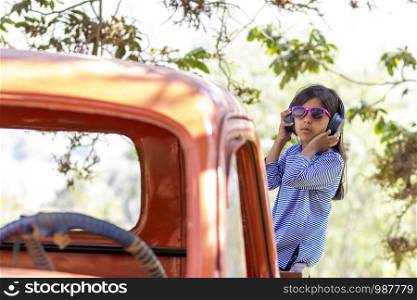 Little girl listening to music with her headphones in the truck car
