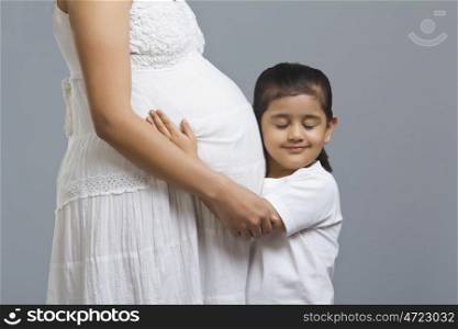 Little girl listening to pregnant womans stomach