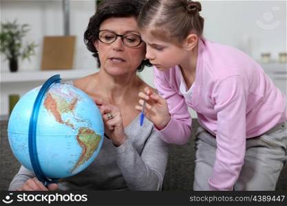 Little girl looking at a globe with her grandmother