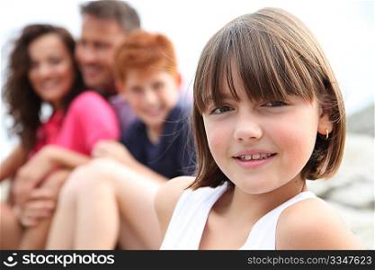 Little girl looking at camera and family in background