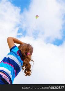 Little girl looking up in the sky on beautiful colorful air kite, rear view, enjoying summer game, flying toy, happy childhood concept