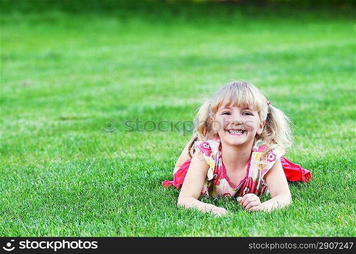 little girl lying on green grass
