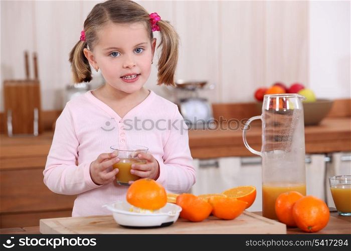 Little girl making orange juice.