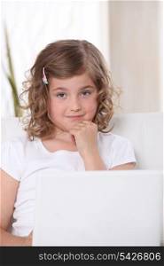 Little girl on a sofa with laptop