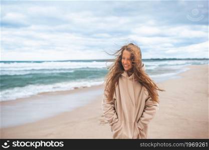 Little girl on the beach in windy and cloudy weather. Young girl on the beach in the storm
