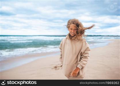 Little girl on the beach in windy and cloudy weather. Young girl on the beach in the storm