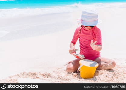 Little girl on the beach plays with sand and makes sandcastle. Little girl at tropical white beach making sand castle