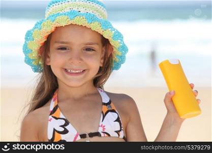 little girl on the beach with a sun cream