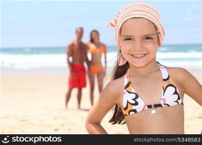 Little girl on the beach with her parents