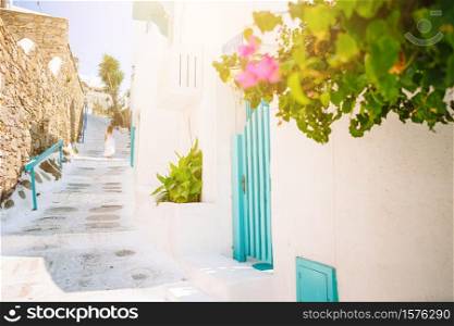 Little girl outdoors in old greek village. Kid at street of typical greek traditional village with white walls and colorful doors on Mykonos Island, in Greece. Girl in white dresses having fun outdoors on Mykonos streets