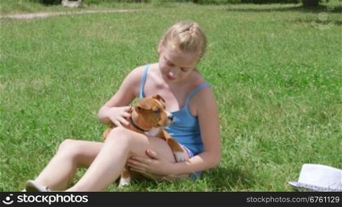 Little girl owner with american staffordshire terrier puppy dog on grass