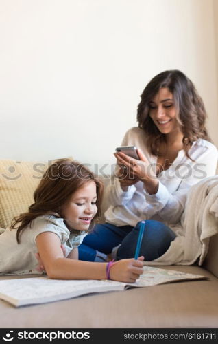 Little girl painting in the living room while mom is on internet