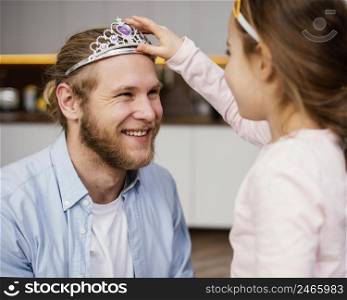 little girl placing tiara father s head