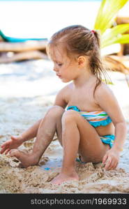 Little girl play with the sand on the beach. Little girl at tropical white beach making sand castle