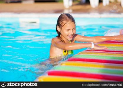 Little girl playing and having fun in swimming pool with air mattress. Kid playing in water. Swimming concept. Girl swim in resort pool during summer vacations