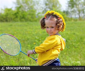 little girl playing badminton on spring meadow