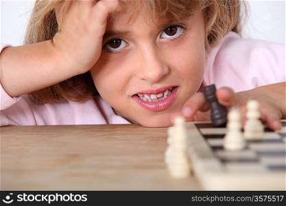 Little girl playing chess alone