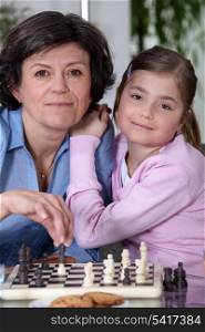 Little girl playing chess with grandmother