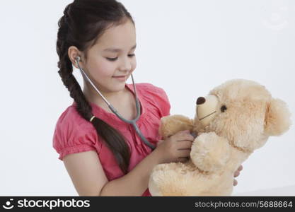 Little girl playing doctor with a teddy bear
